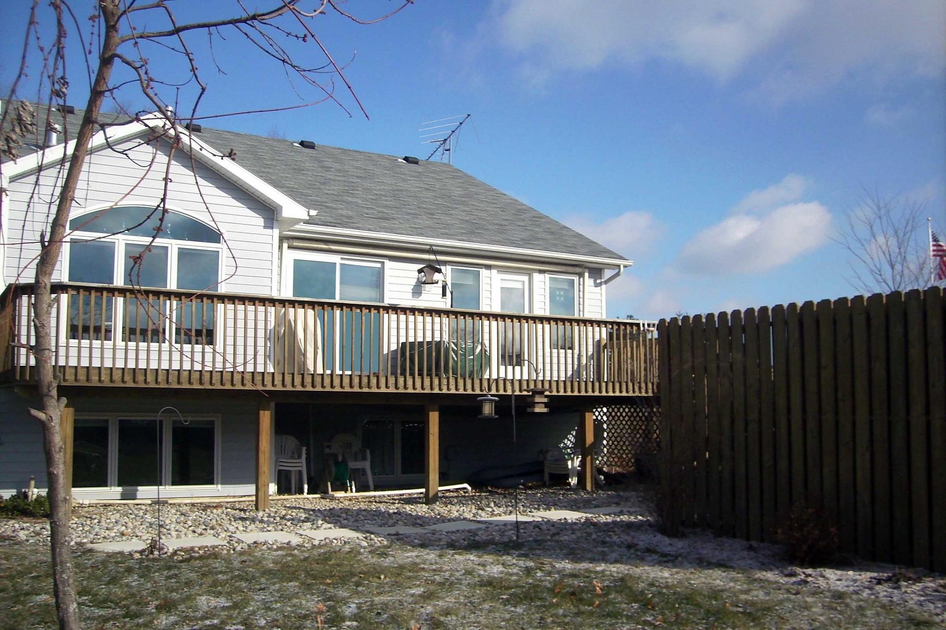 A house with a large deck and a fence in front of it