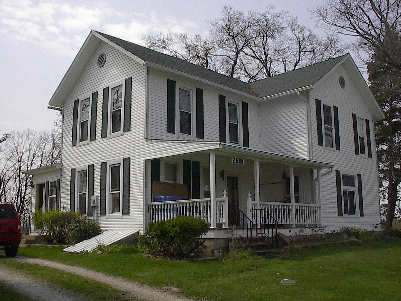 A large white house with black shutters and a porch