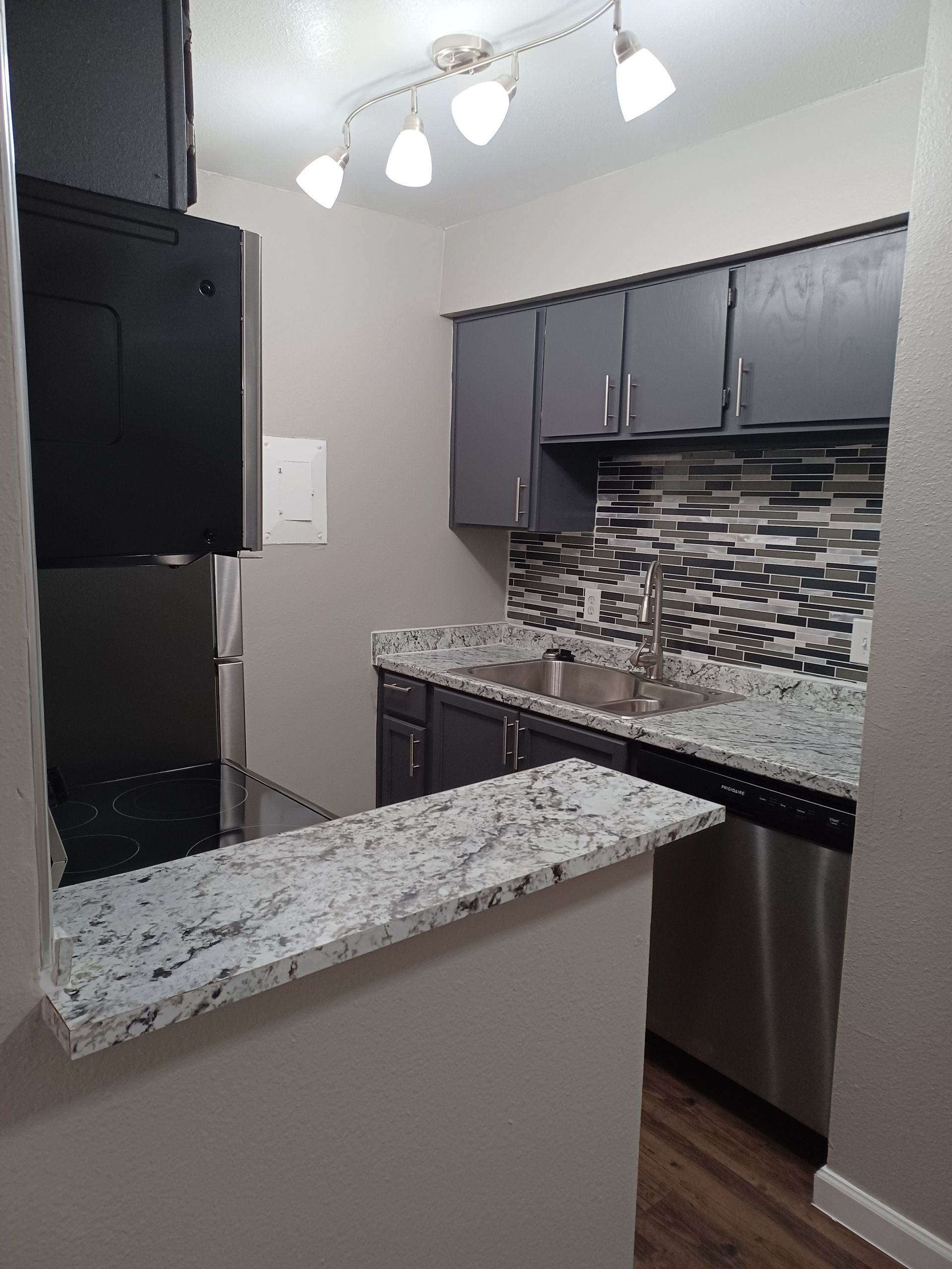 Modern kitchen with gray cabinets, granite countertops, and stainless steel appliances.