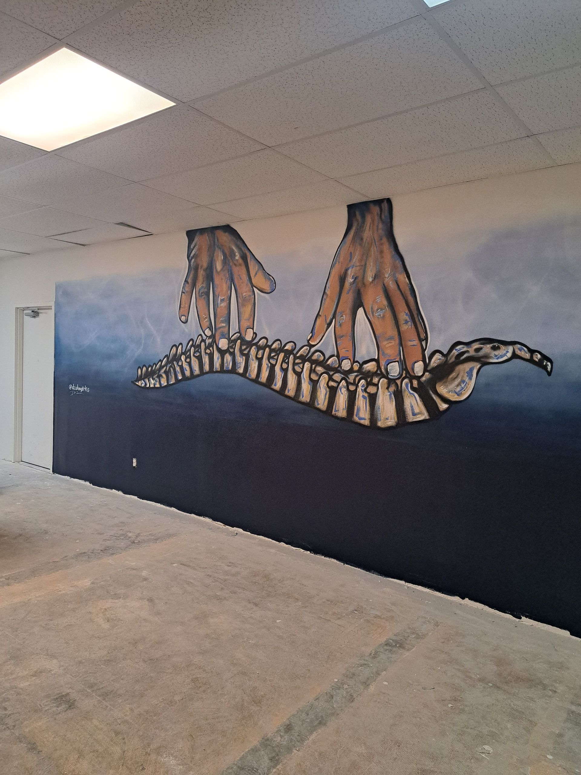 Mural of two hands manipulating a spine shape over a dark blue background on an interior wall.