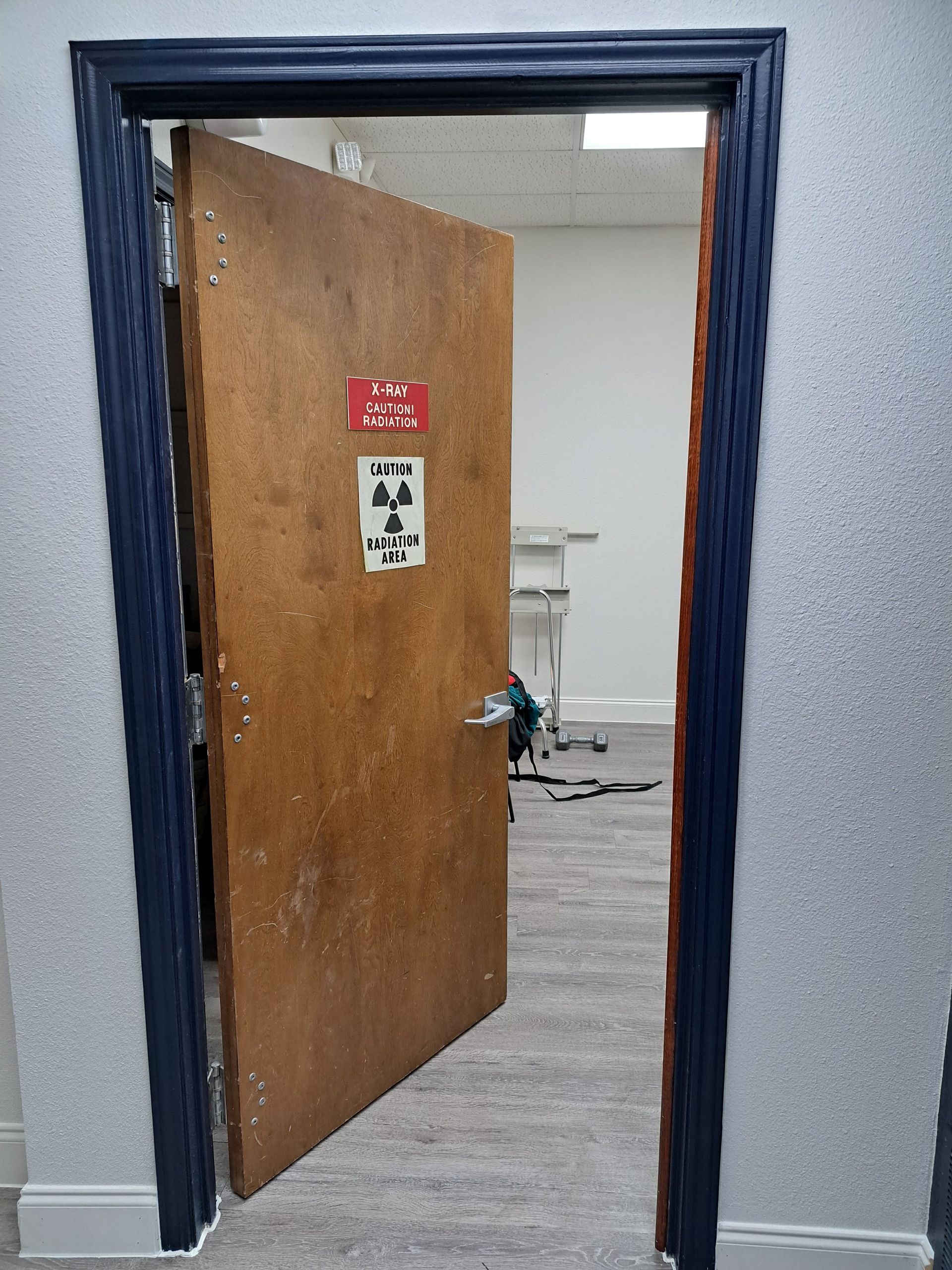 Doorway with blue trim, wooden door slightly ajar, revealing an interior room with a fireplace and equipment.
