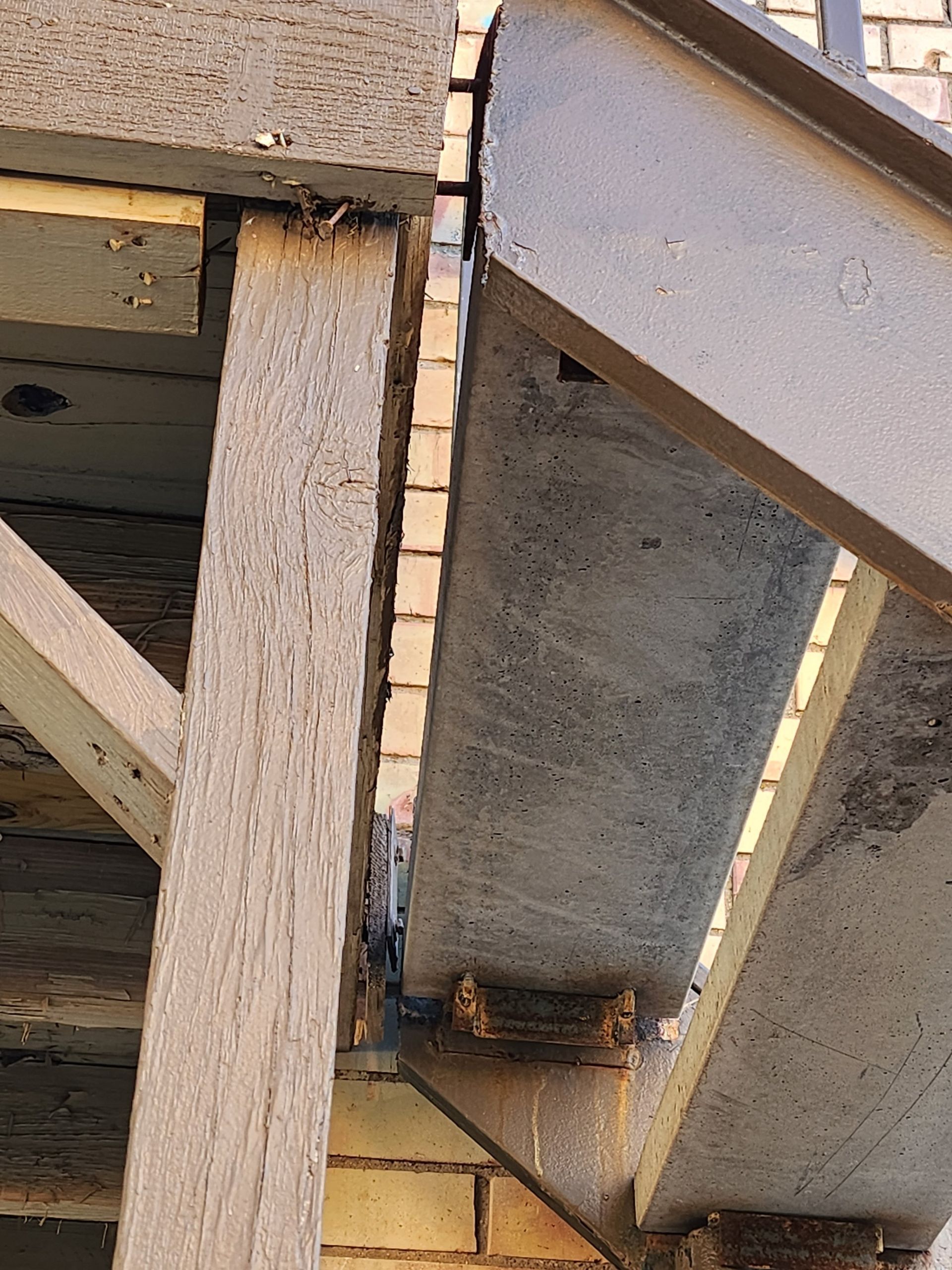 Exterior staircase with concrete steps and steel supports next to a brick wall.