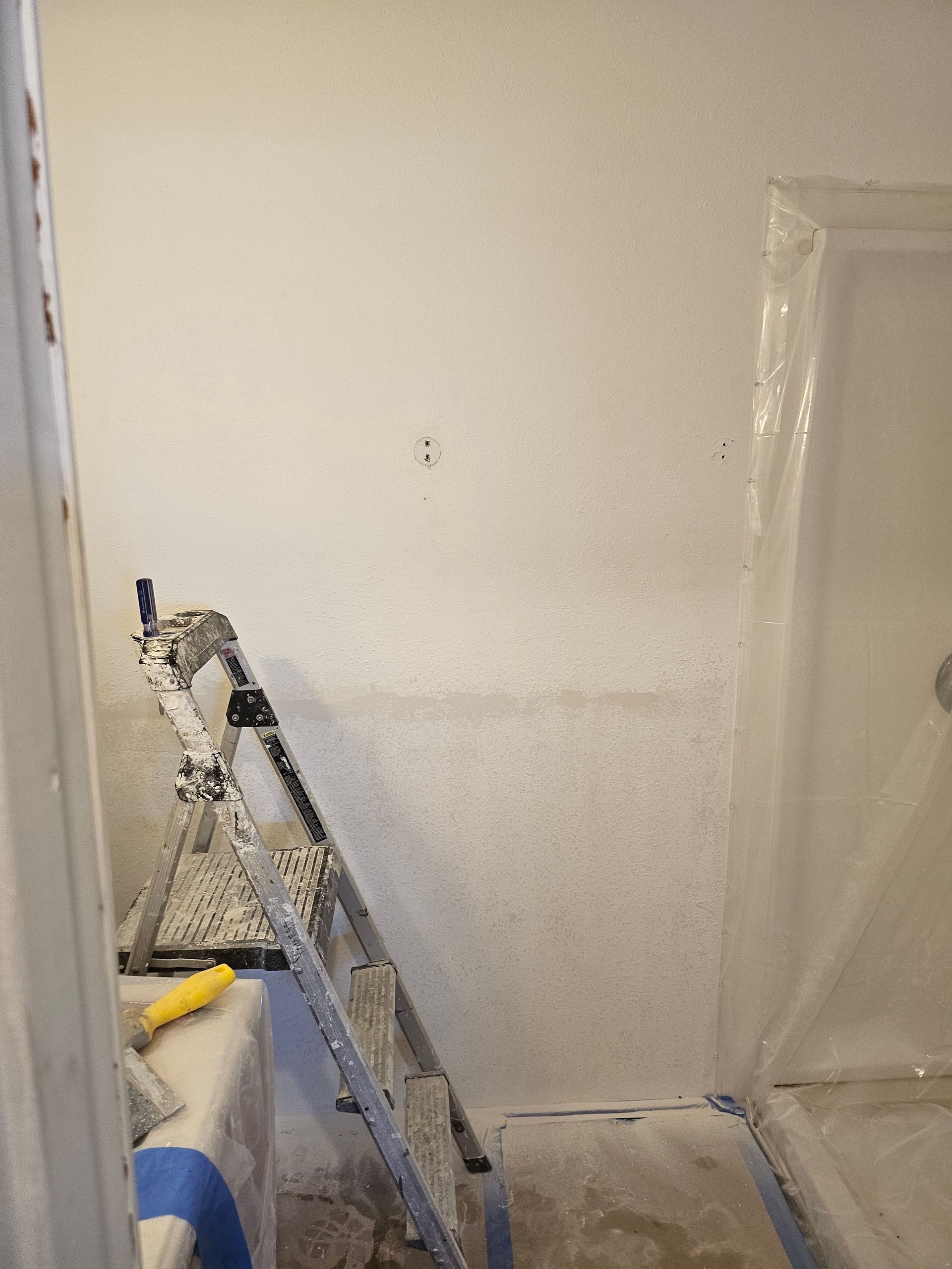 Interior wall being painted; ladder and supplies present.