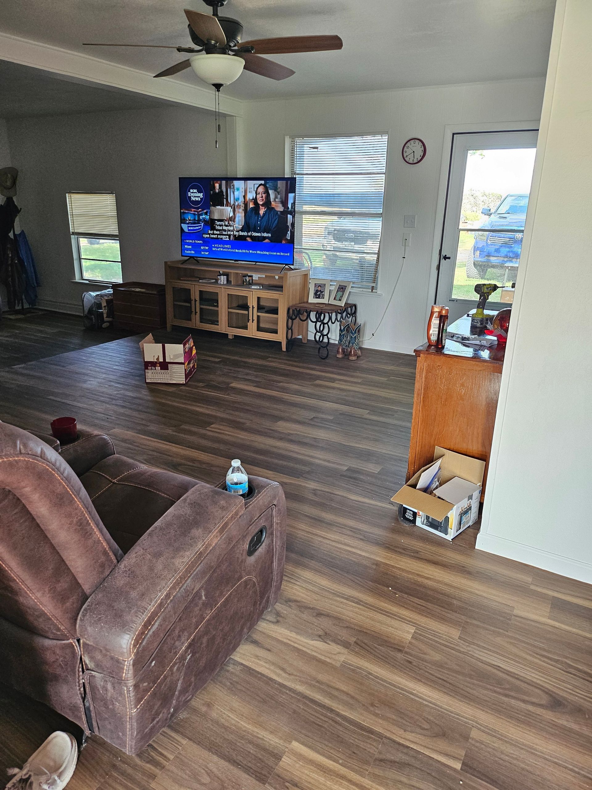 Living room with TV on wooden cabinet, recliner, and boxes on the floor.
