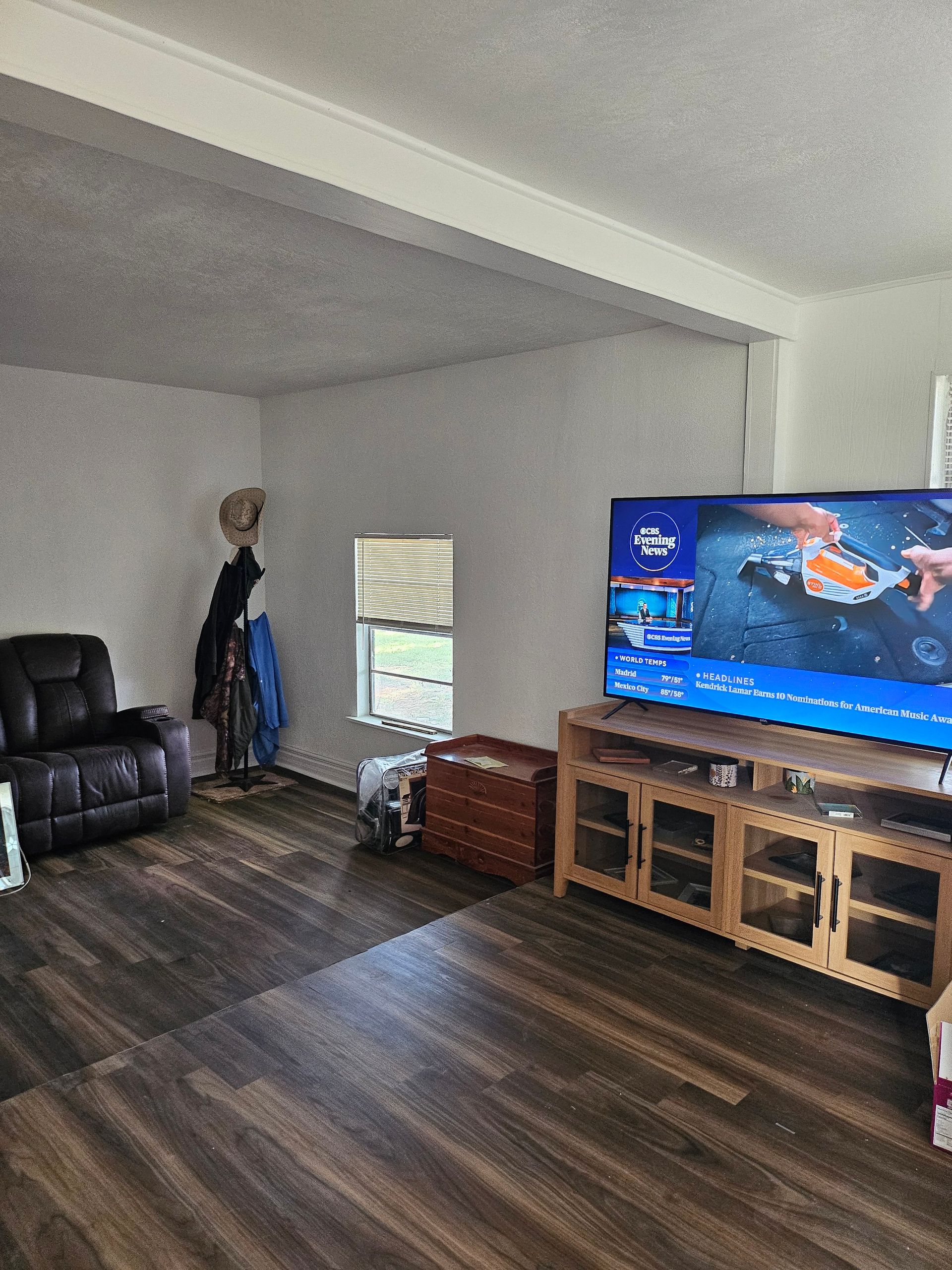 Living room with a recliner, TV on a wooden stand, and a small window.
