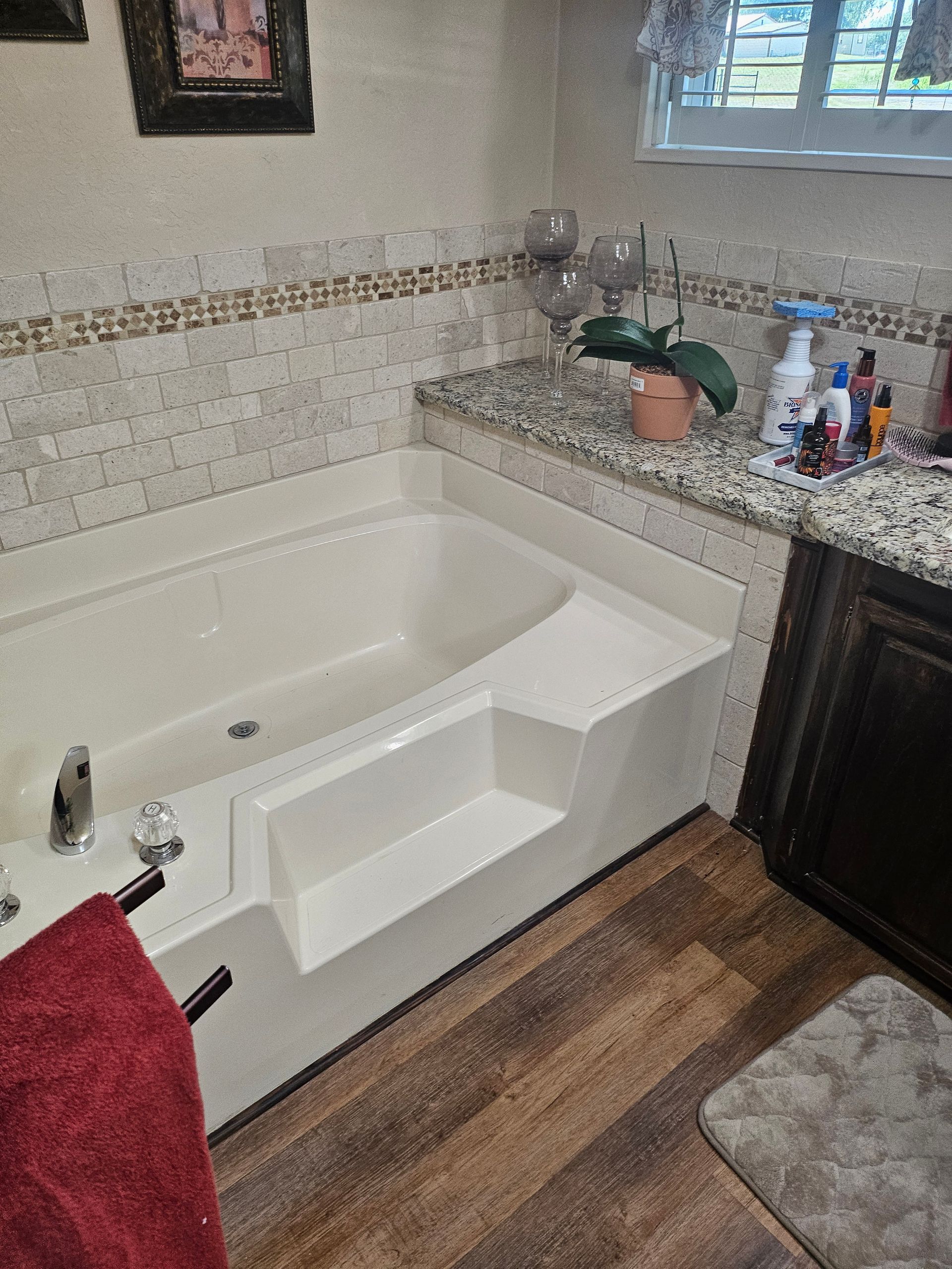 A built-in white bathtub with steps, next to a countertop with toiletries.