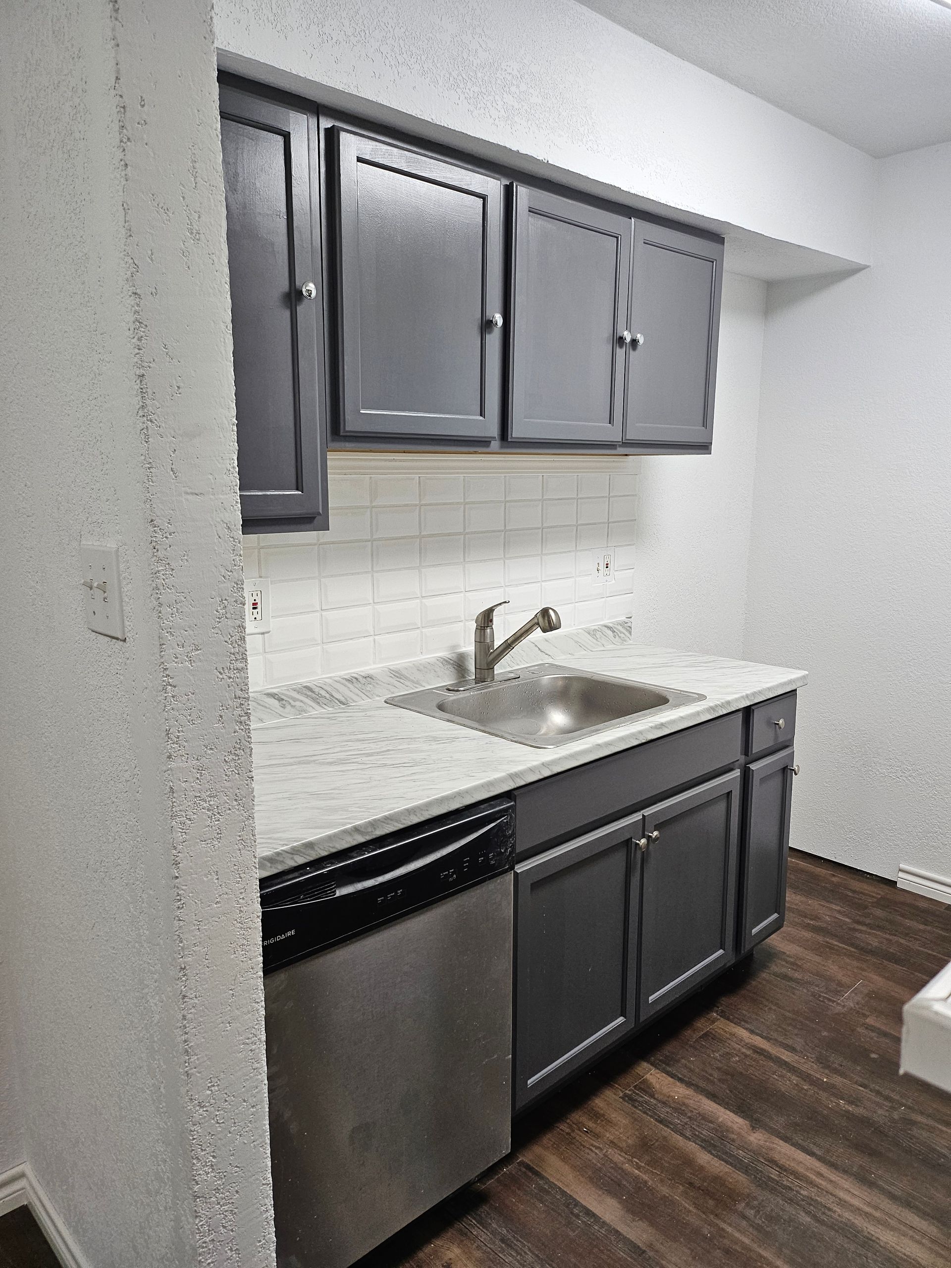 Small kitchen with gray cabinets, stainless steel appliances, and white countertops.