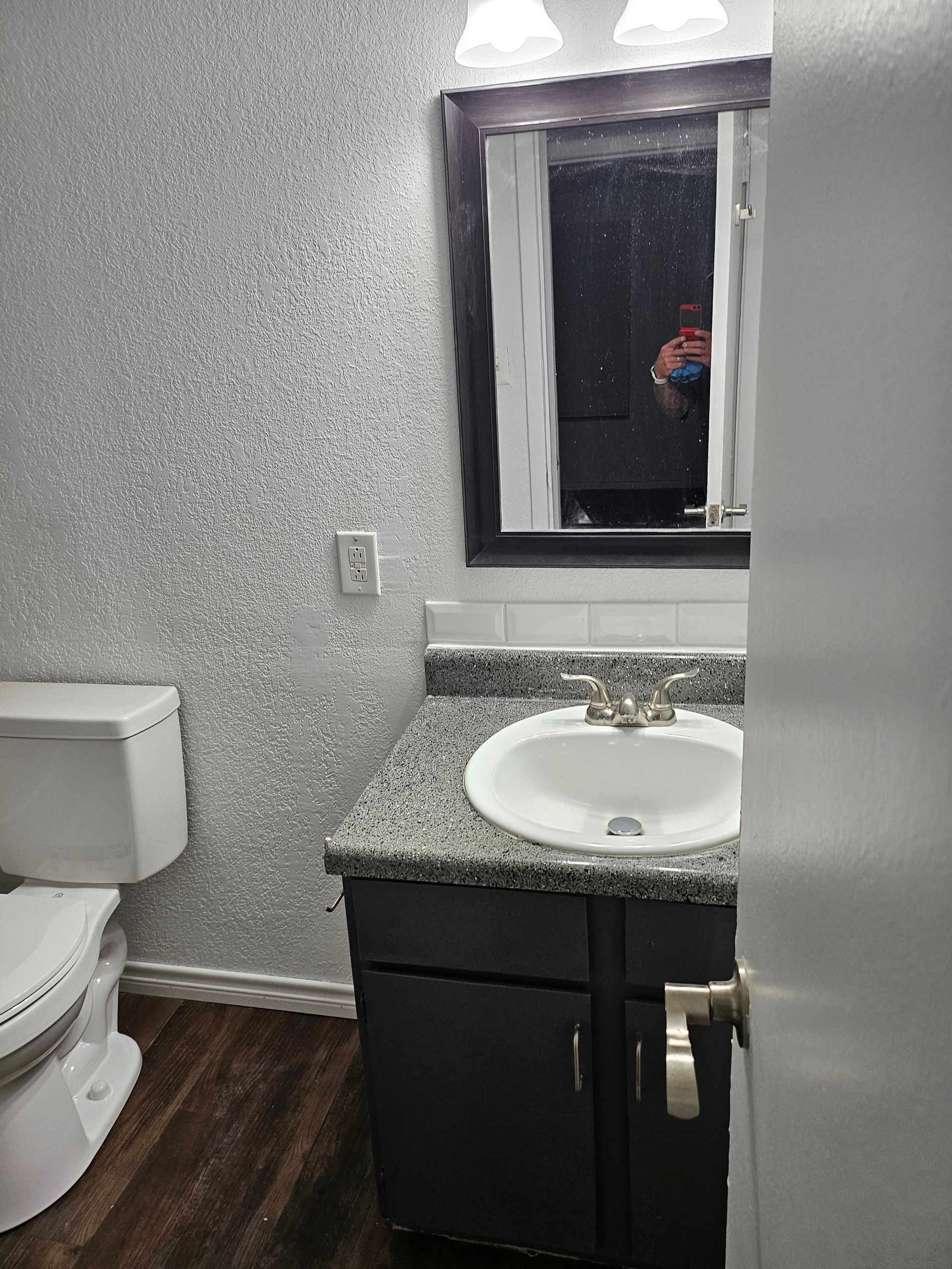 Small bathroom with glittery silver walls, toilet, vanity, and mirror.