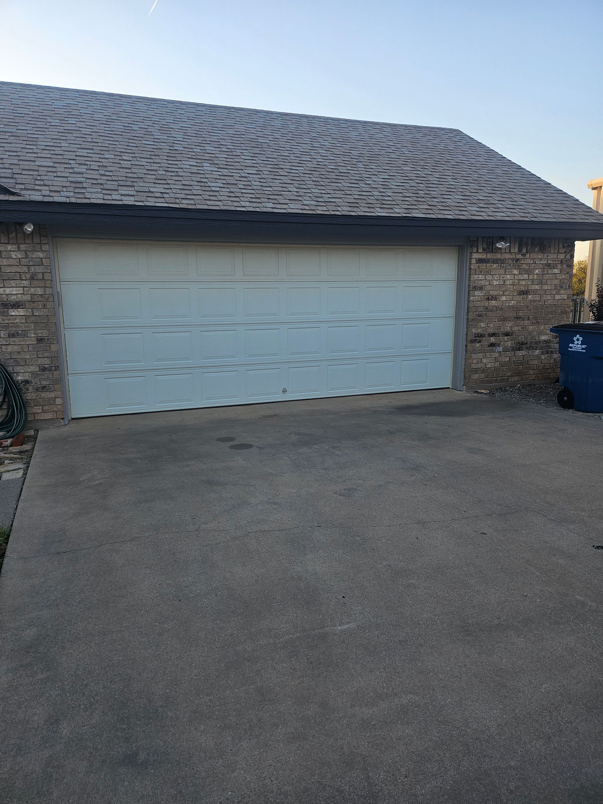 Garage with a gray concrete driveway and brick siding.