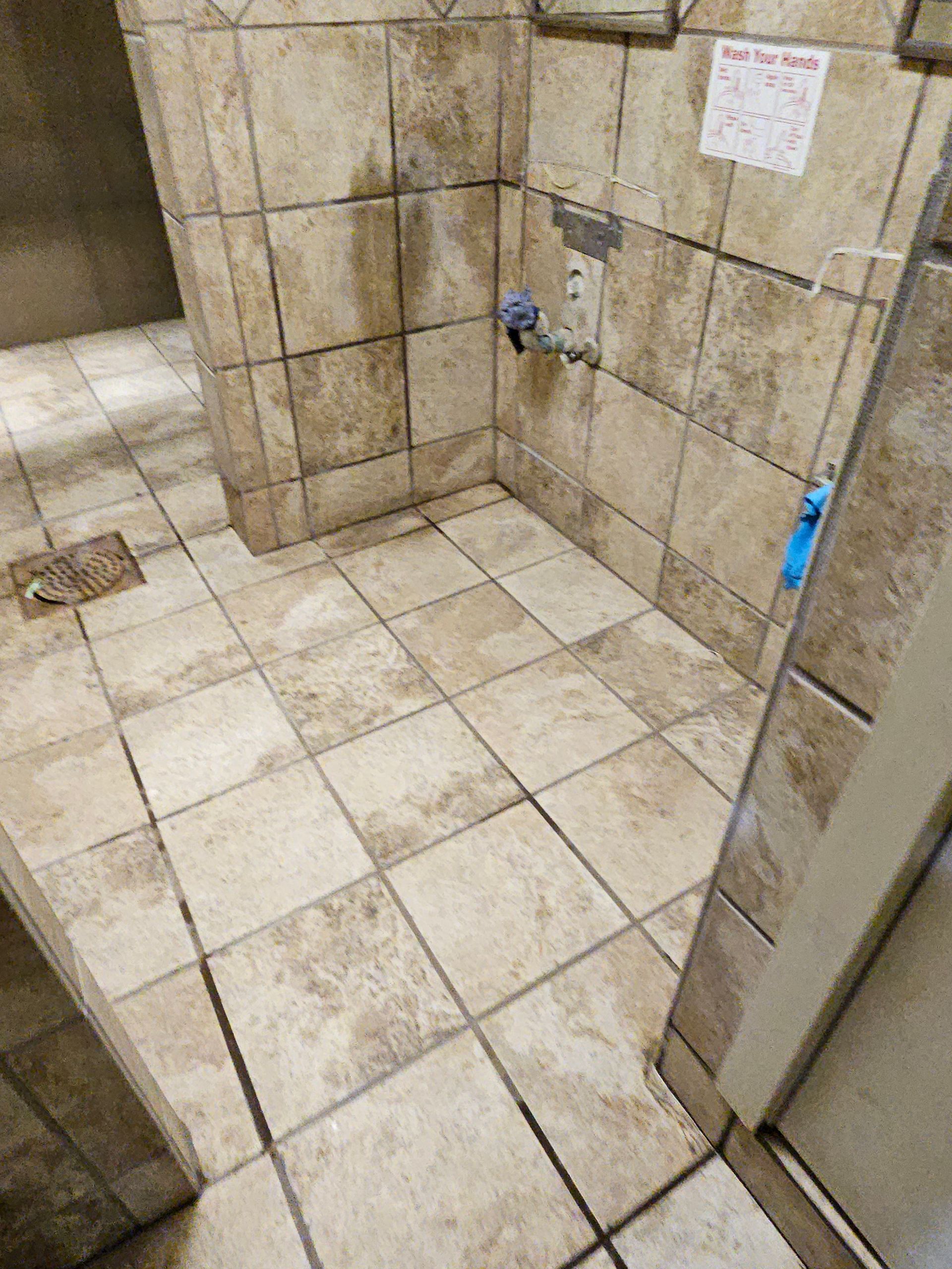 Tiled bathroom stall with a sink, potentially wet floor.