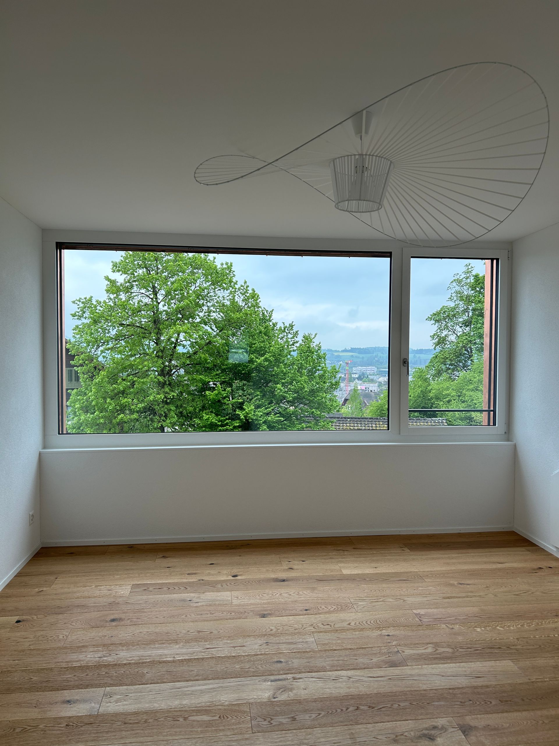 Ein weißes Haus mit Balkon ist von Gras und Bäumen umgeben