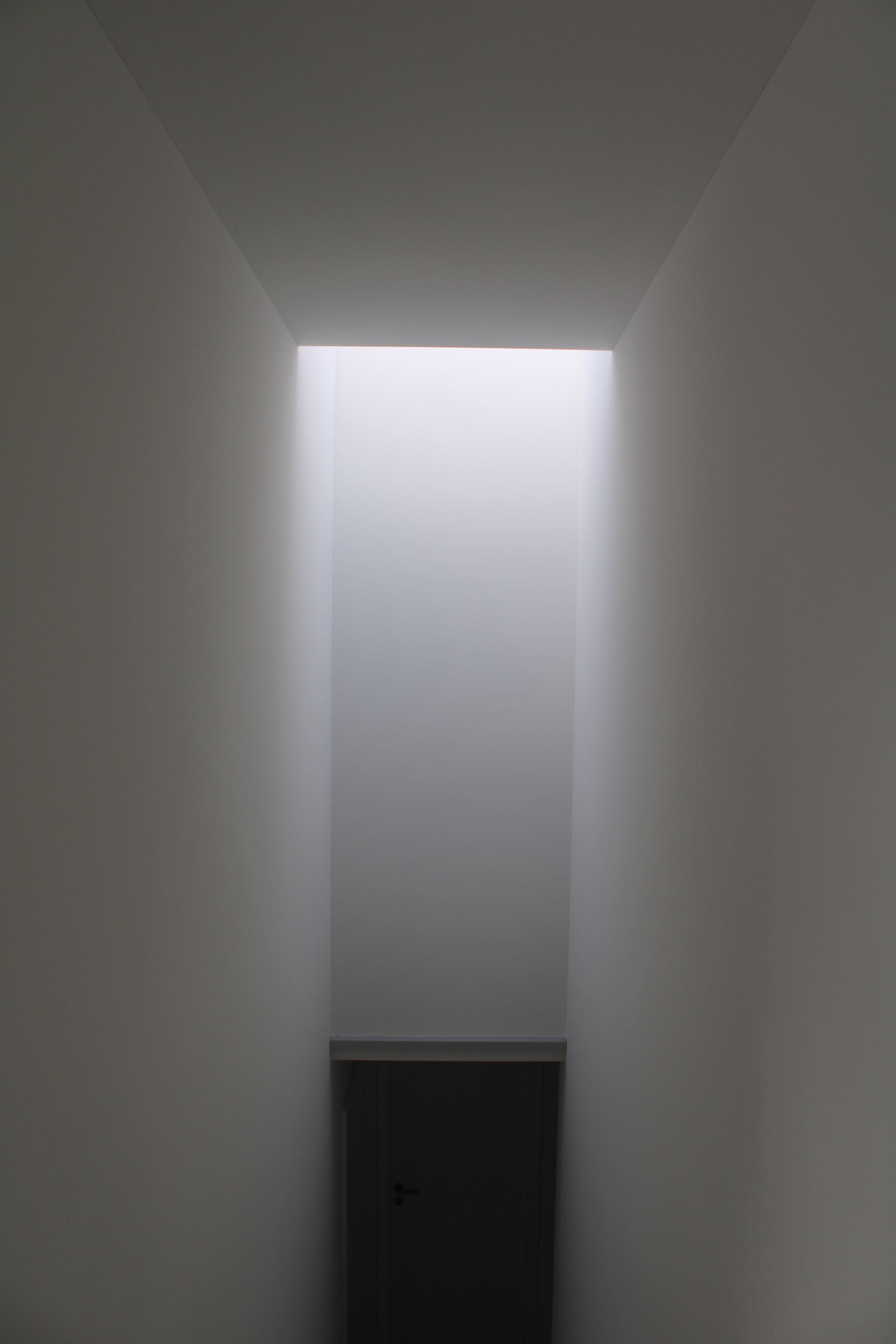 In einem dunklen Raum scheint durch ein Loch in der Wand ein Licht.