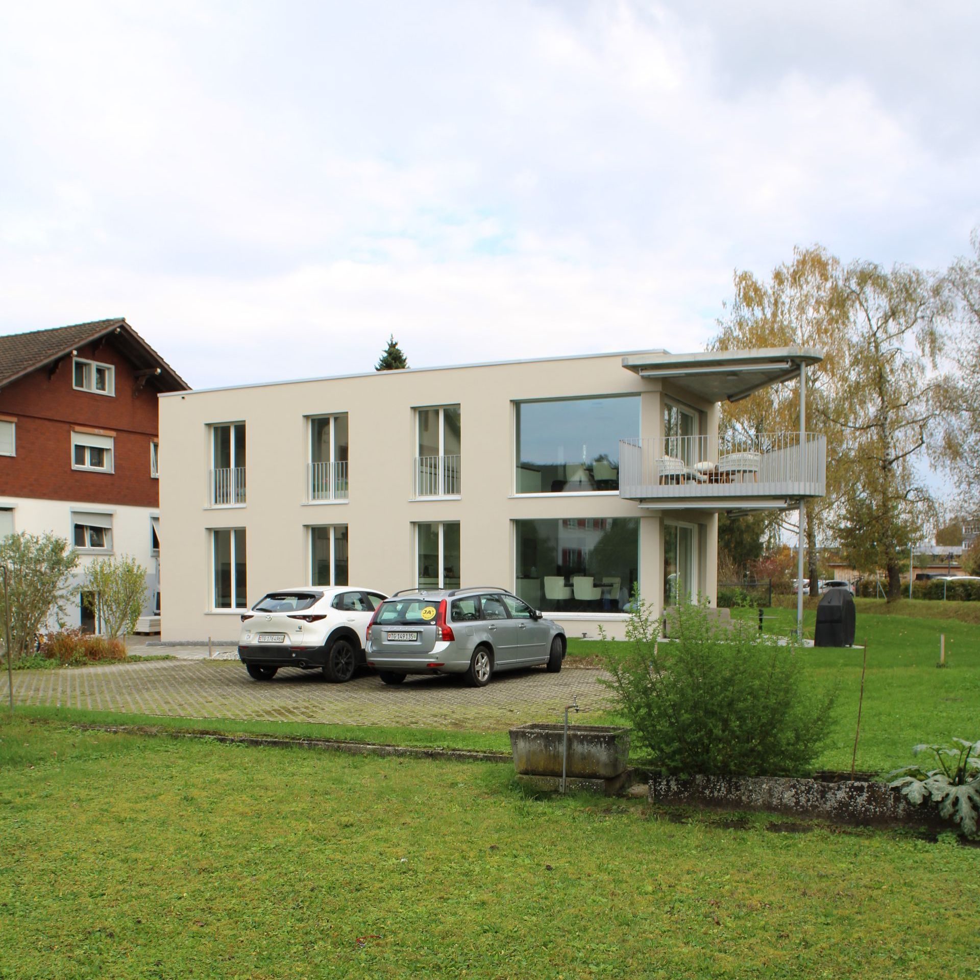 Ein Haus mit vielen Fenstern und davor geparkten Autos