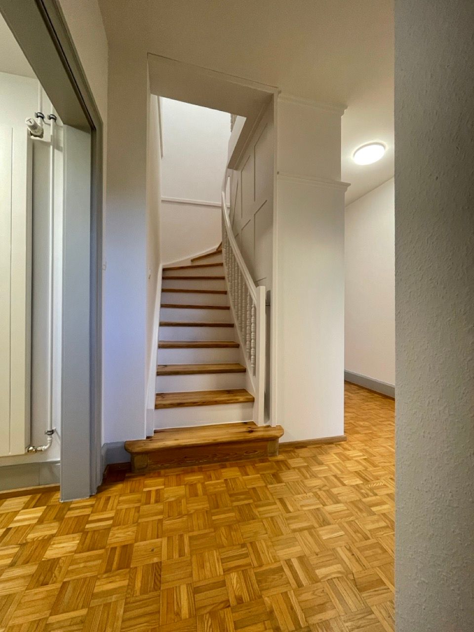 Ein Flur mit Holzboden und Treppe zum zweiten Stock