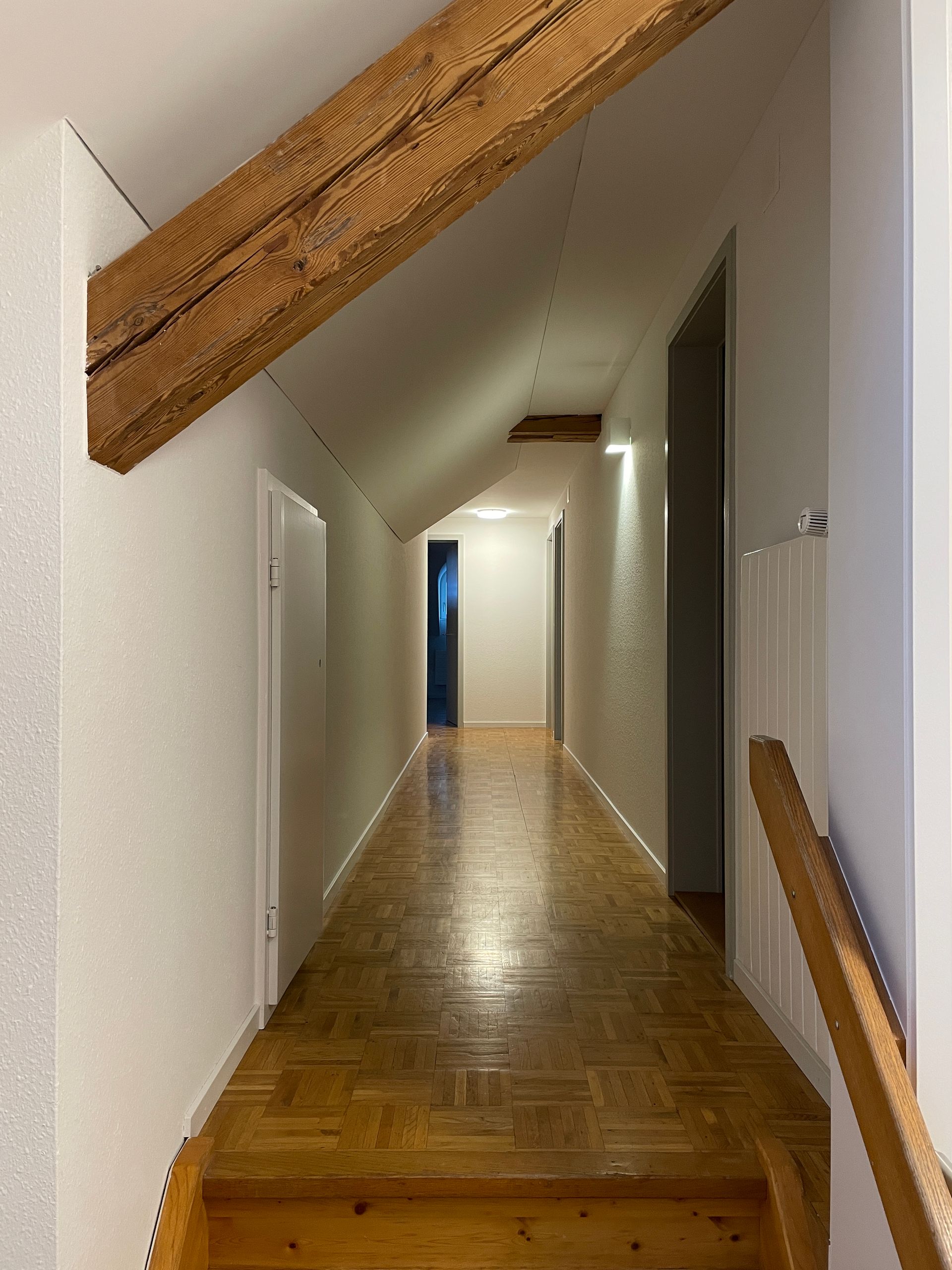 Ein Flur mit Holzboden und Treppe zum zweiten Stock