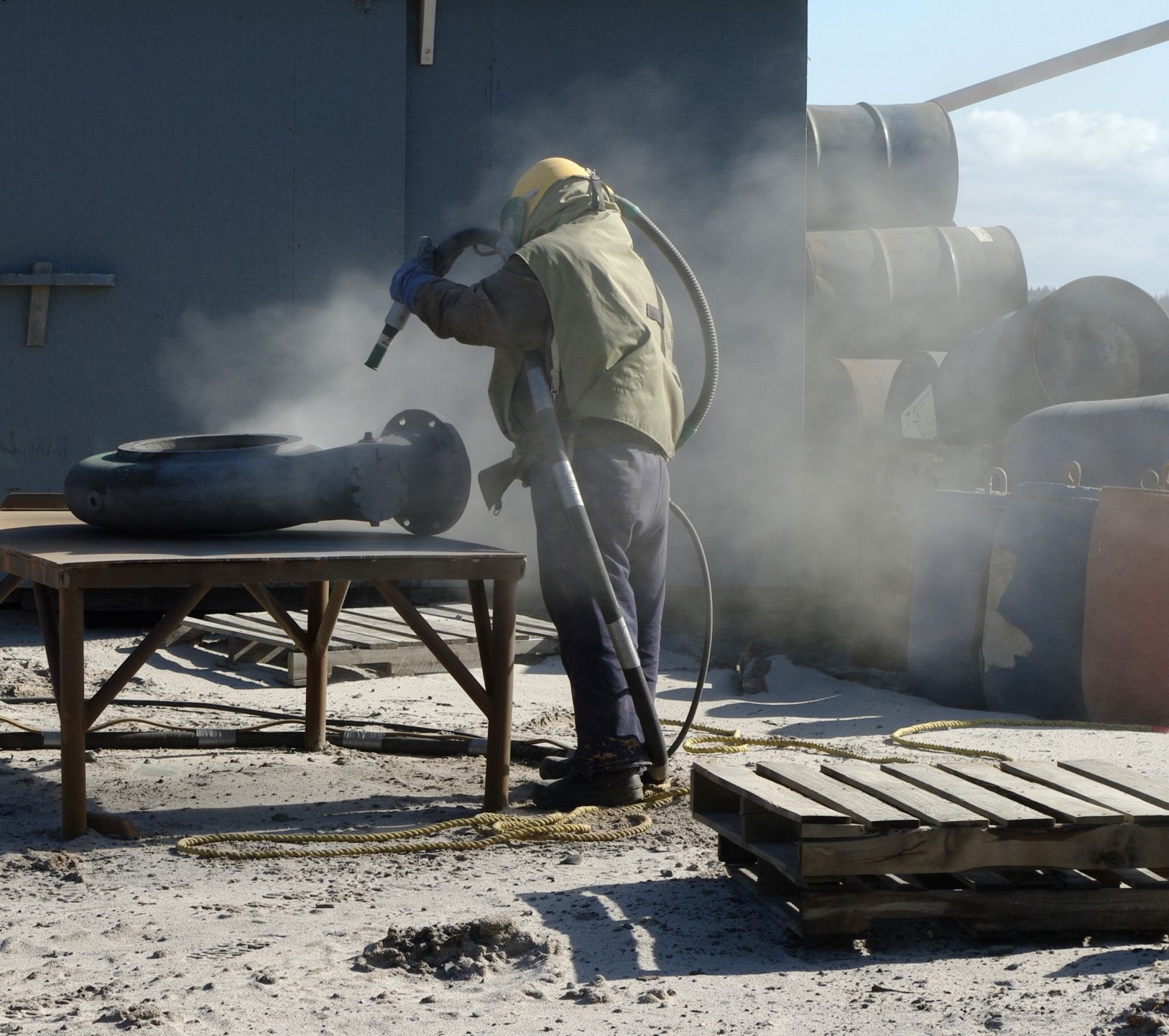A man wearing a helmet is sandblasting a tire