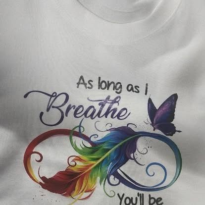 A white t-shirt with a rainbow feather and a butterfly on it.