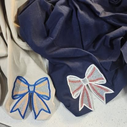 Two pieces of cloth with bows embroidered on them
