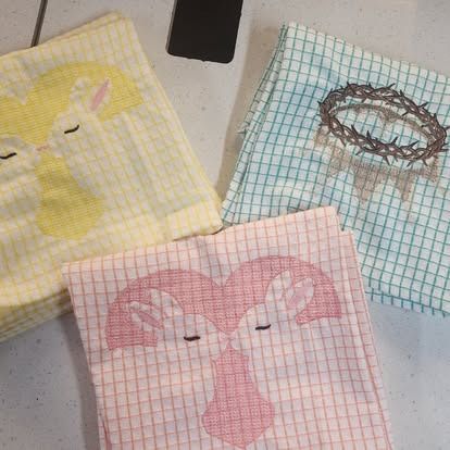 Three towels with a crown of thorns on them are sitting on a table.