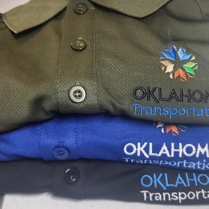 Three oklahoma transportation polo shirts are stacked on top of each other
