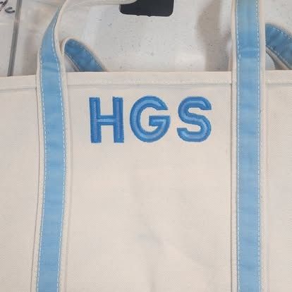 A white tote bag with the word hgs embroidered on it