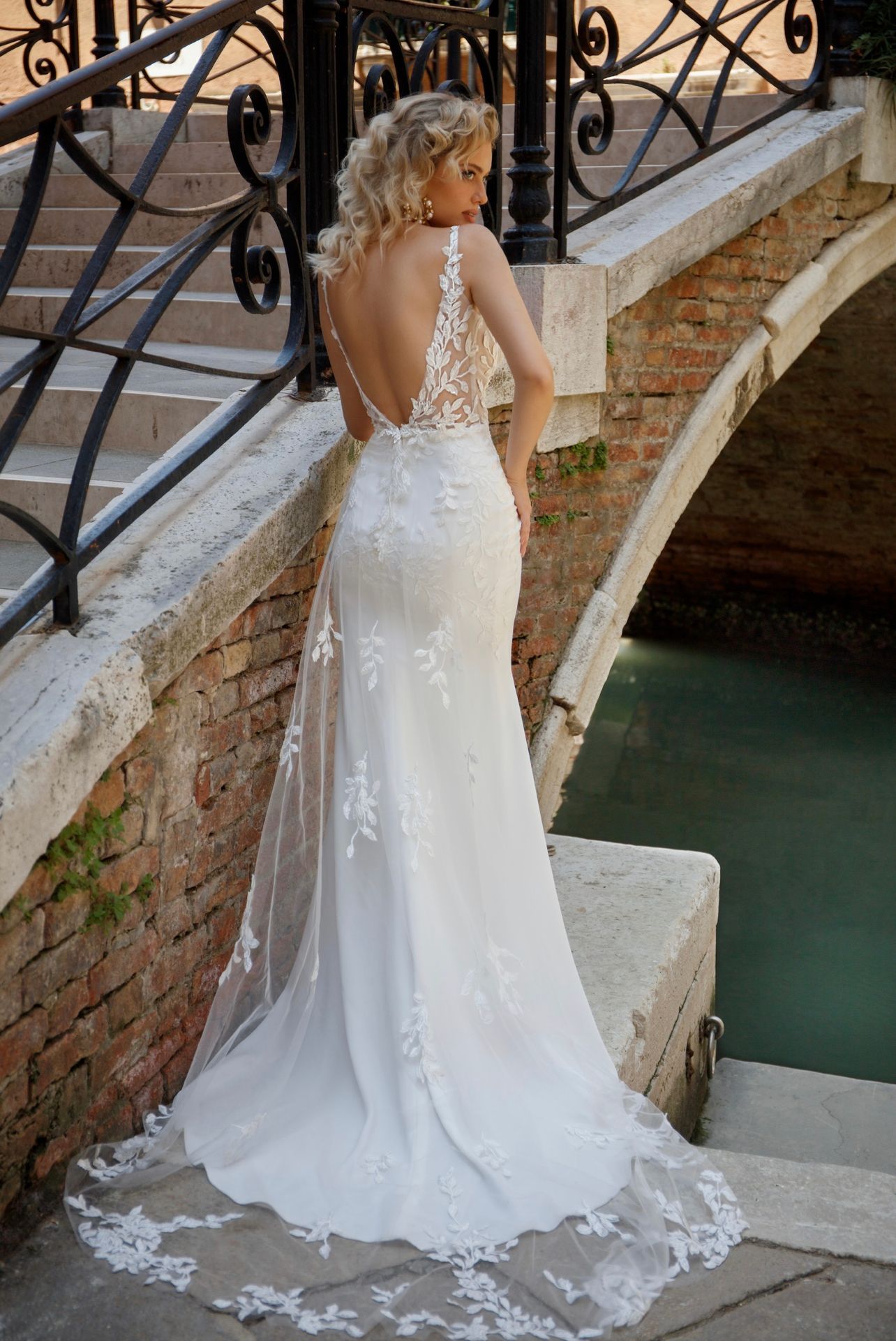 Eine Frau in einem Brautkleid steht neben einer Brücke.