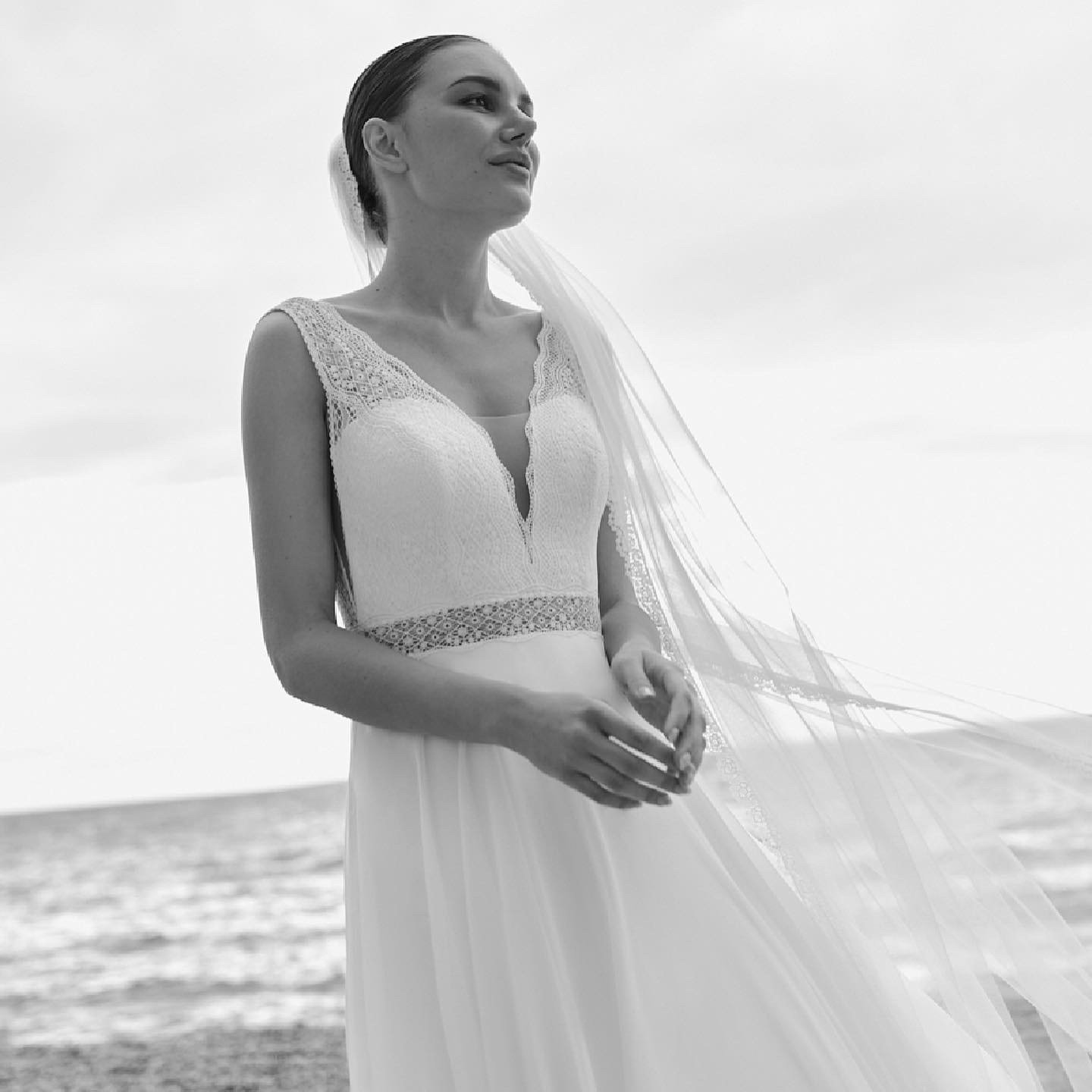 Eine Frau in einem Brautkleid und Schleier steht am Strand.