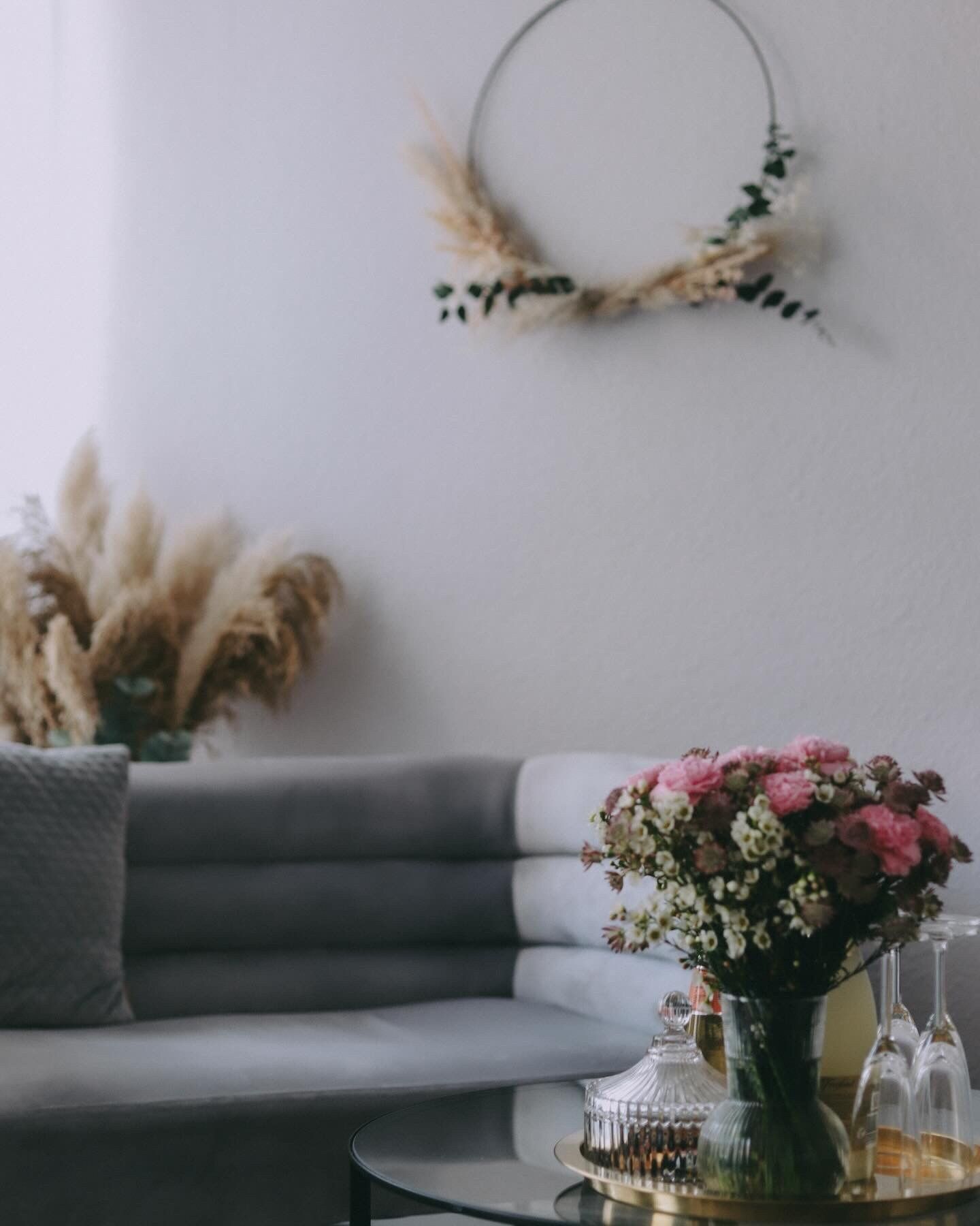 Ein Wohnzimmer mit einer Couch und einer Vase mit Blumen auf einem Tisch.