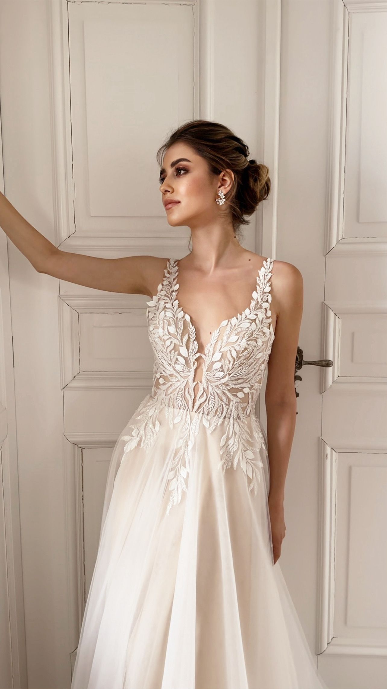 Eine Frau in einem Brautkleid steht vor einer weißen Tür.