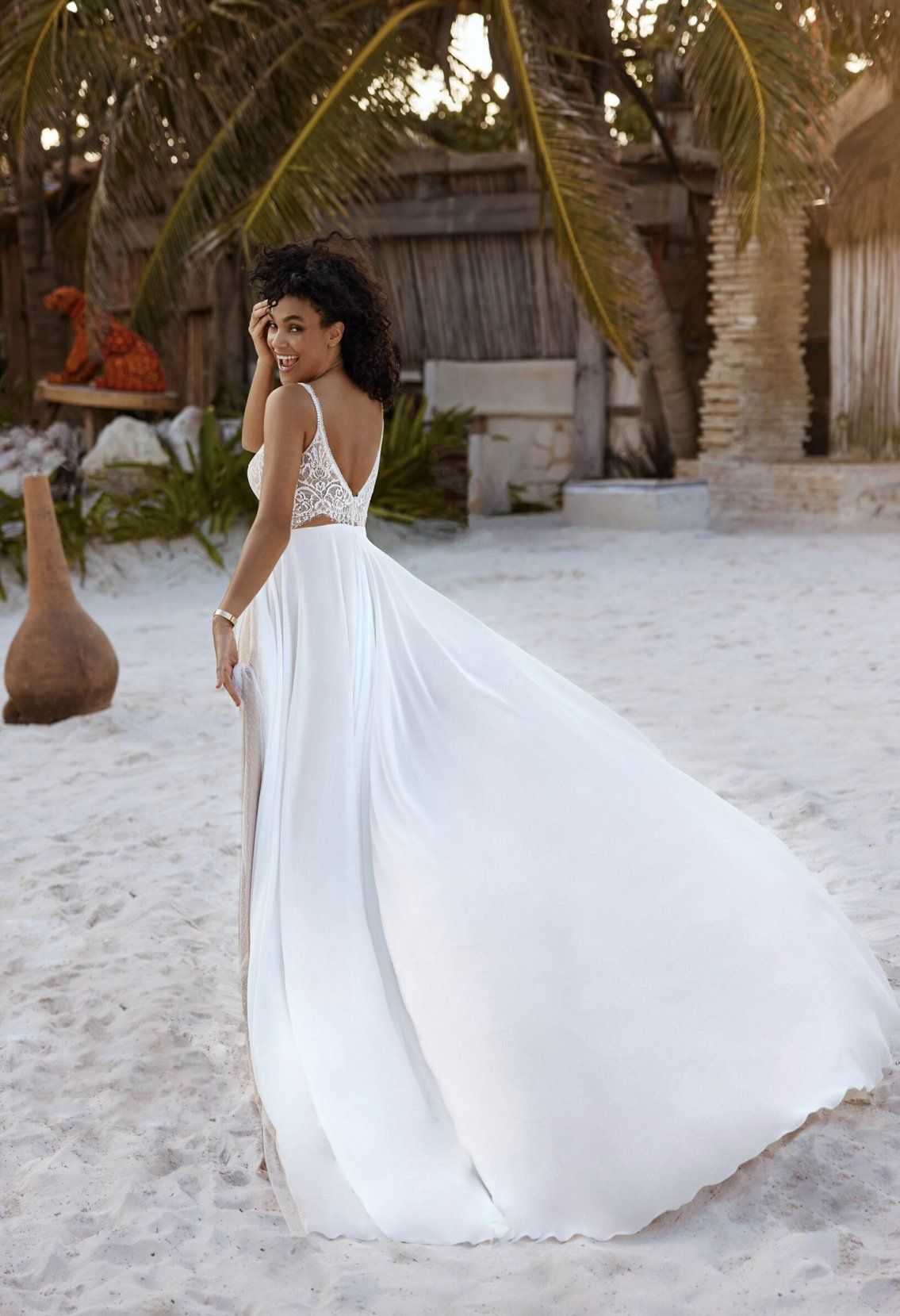 Eine Frau in einem weißen Hochzeitskleid steht an einem Strand.