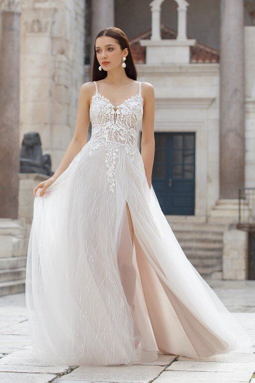 Eine Frau in einem weißen Brautkleid steht vor einem Gebäude.