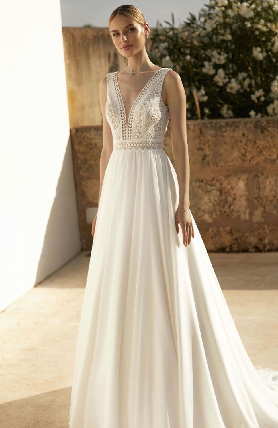 Eine Frau trägt ein weißes Hochzeitskleid mit tiefem Ausschnitt.