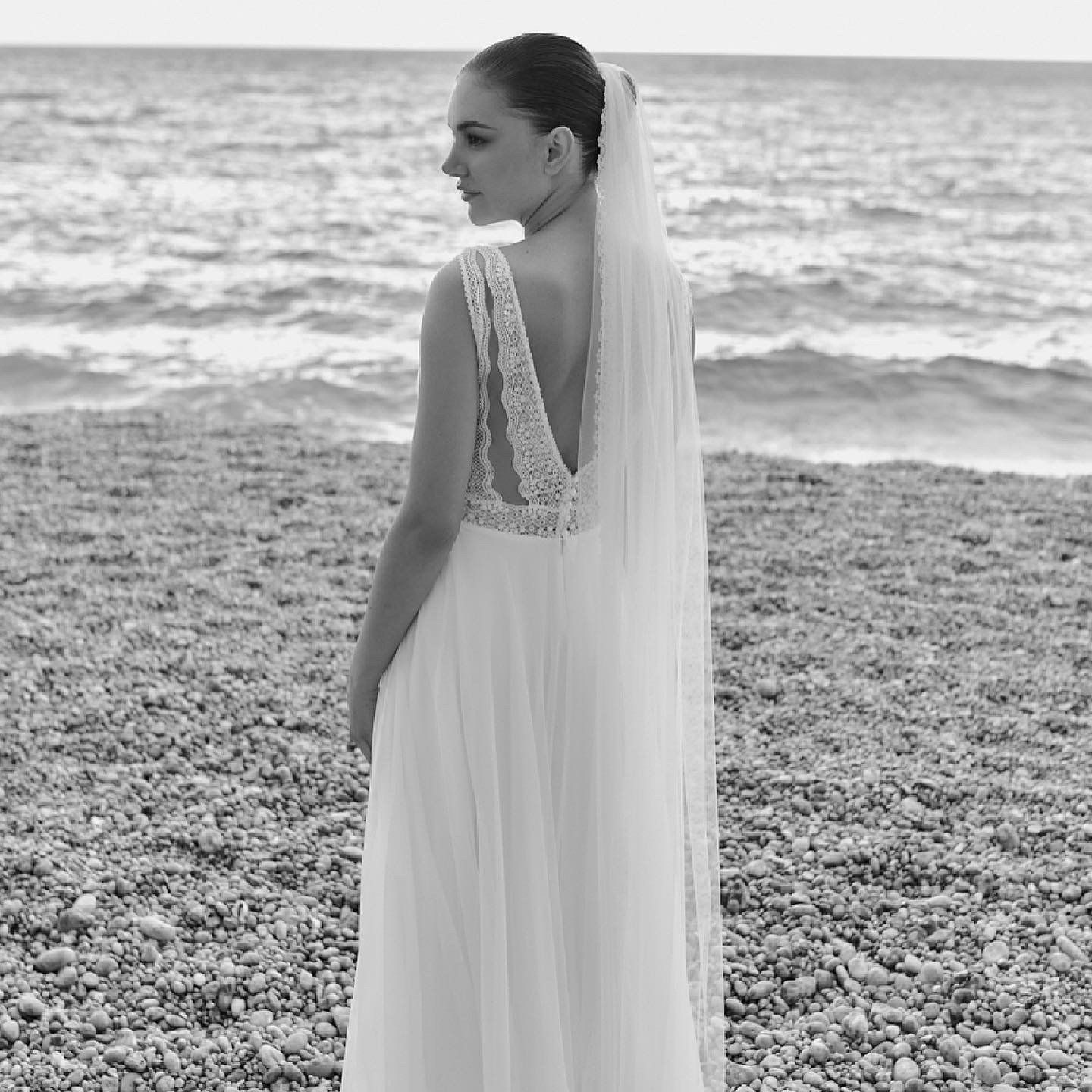 Eine Frau in einem Brautkleid und Schleier steht an einem Strand.