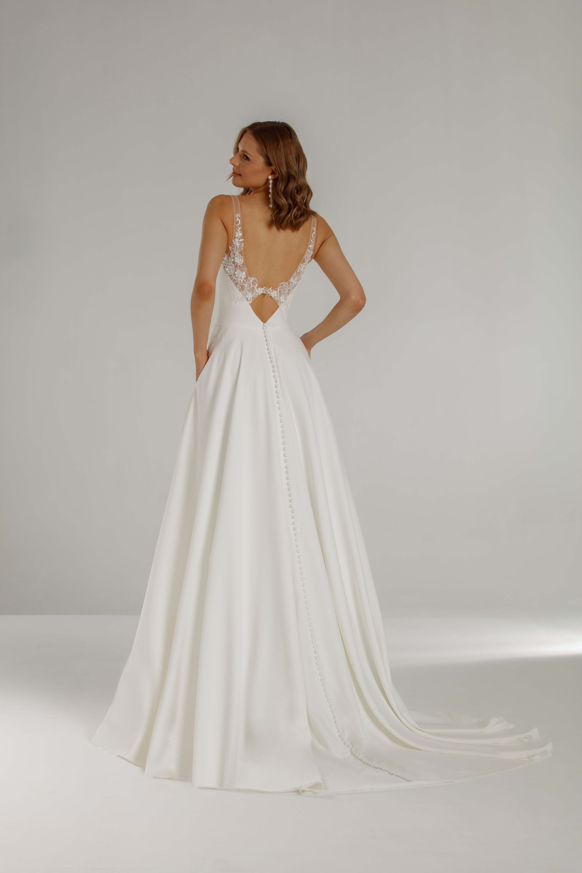Eine Frau trägt ein weißes Hochzeitskleid mit tiefem Ausschnitt.