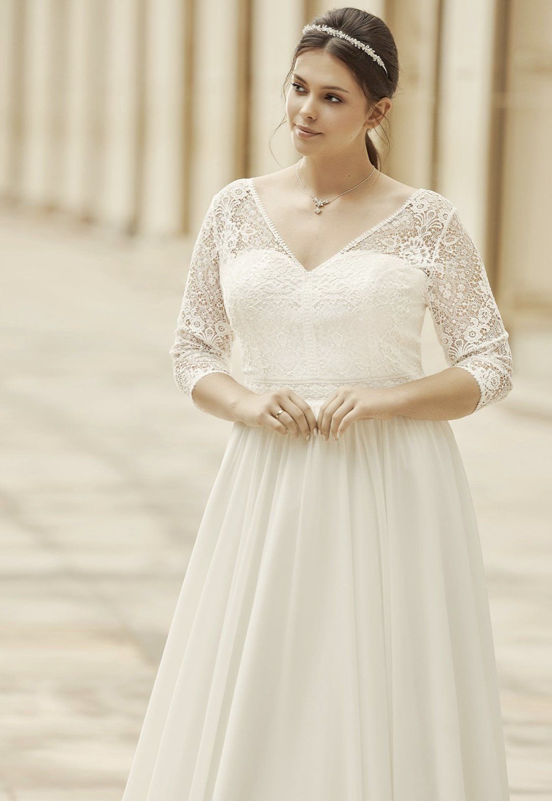 Eine Frau in einem weißen Brautkleid steht vor einem Gebäude.