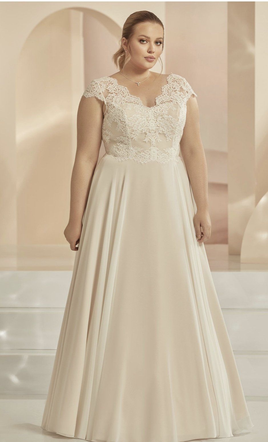 Eine Frau mit Übergröße trägt ein weißes Hochzeitskleid.