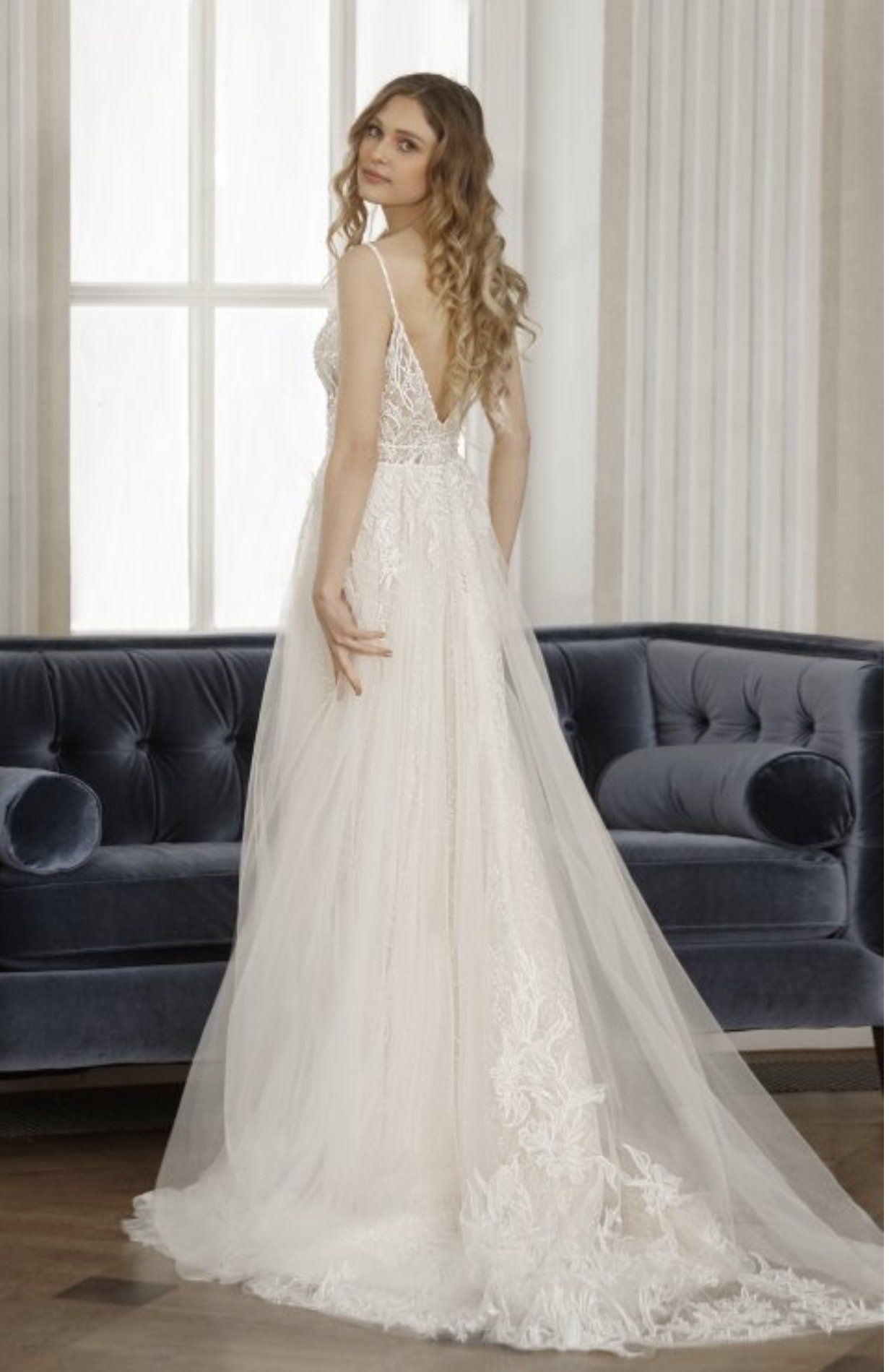Eine Frau in einem Brautkleid steht vor einem Sofa.
