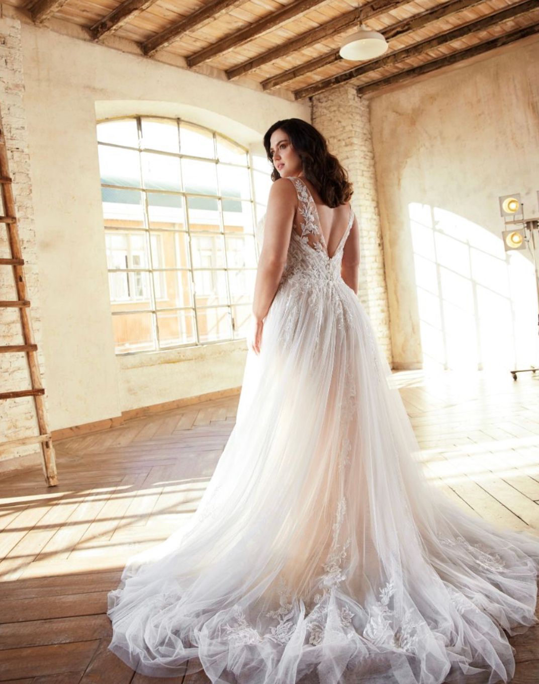 Eine Frau in einem Brautkleid steht in einem Raum mit einer Leiter.