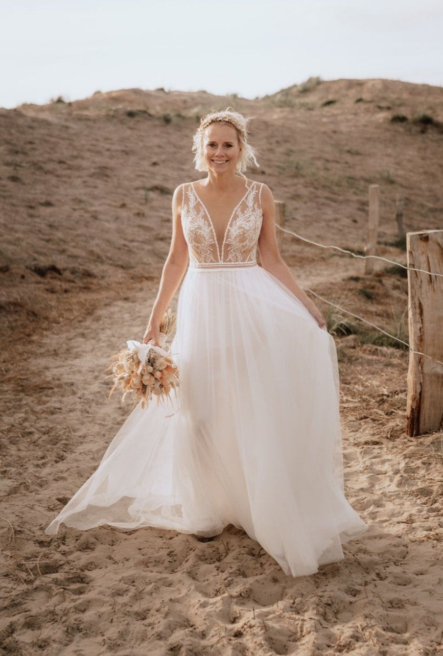 Die Braut trägt ein weißes Brautkleid und hält einen Blumenstrauß.