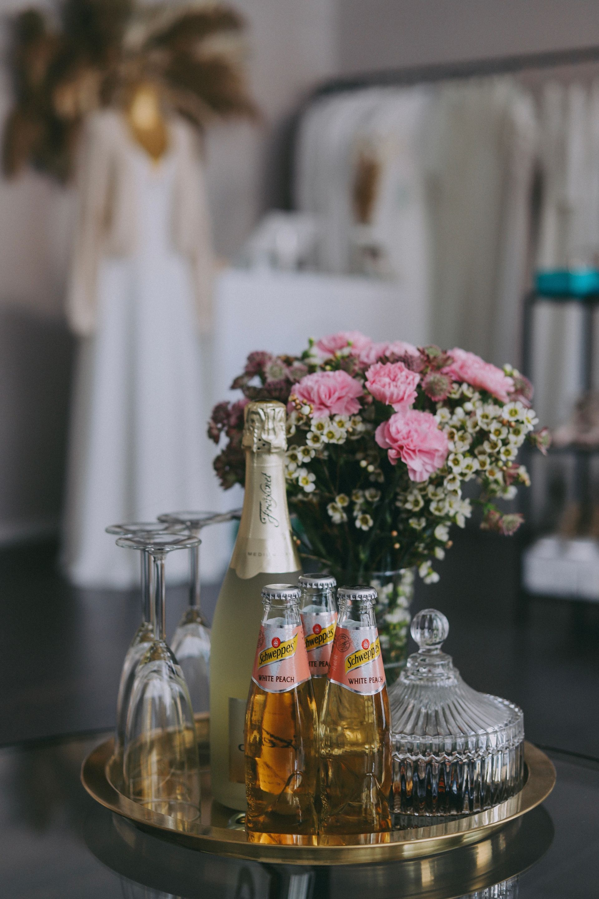 Ein Tablett mit einer Flasche Champagner, Gläsern und Blumen darauf.
