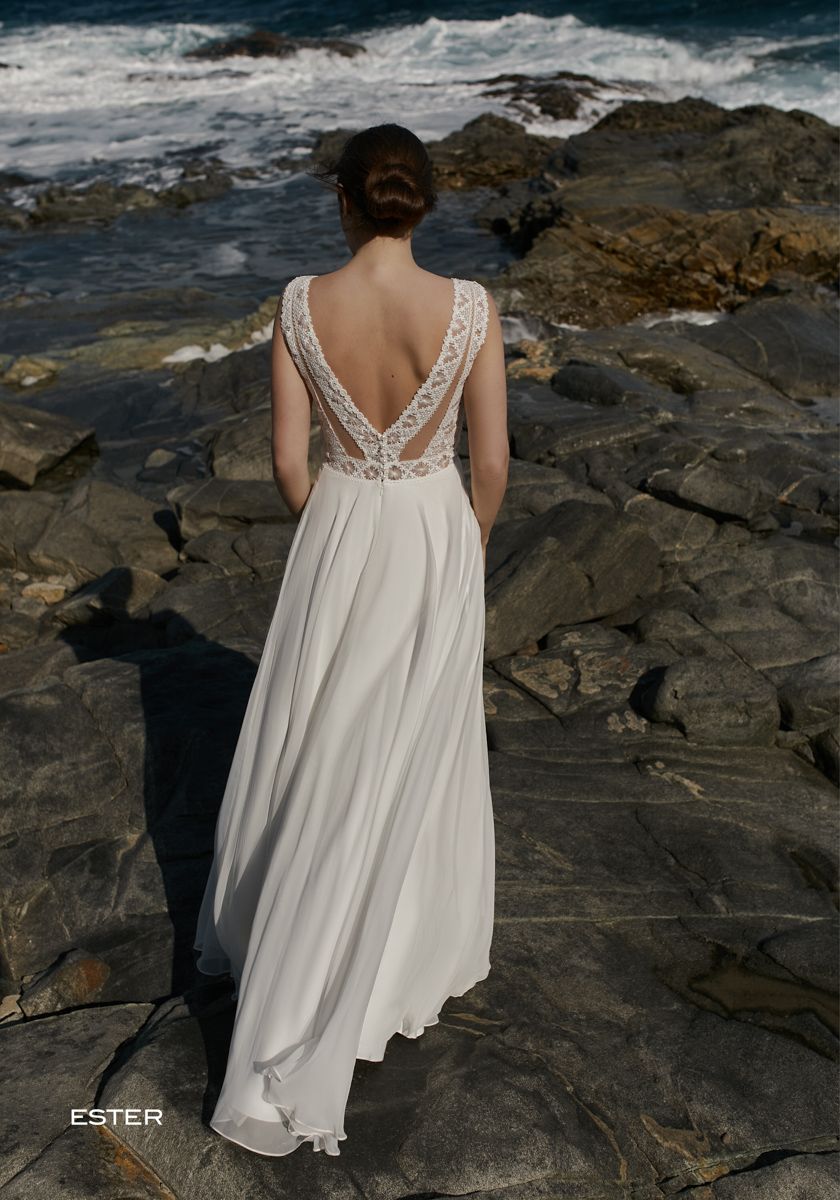 Eine Frau in einem Brautkleid steht an einem felsigen Strand in der Nähe des Meeres.