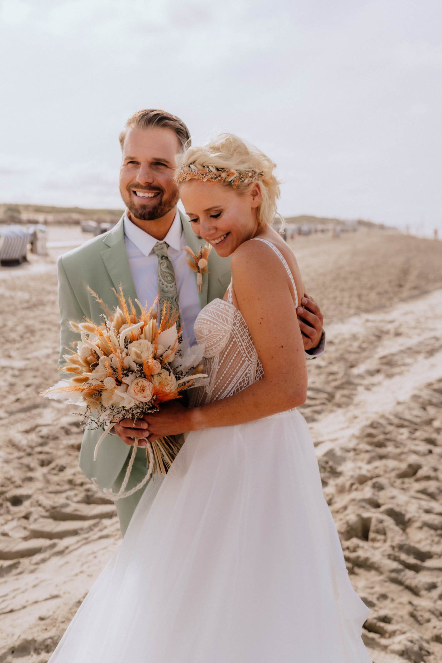Eine Braut und ein Bräutigam posieren für ein Foto am Strand.