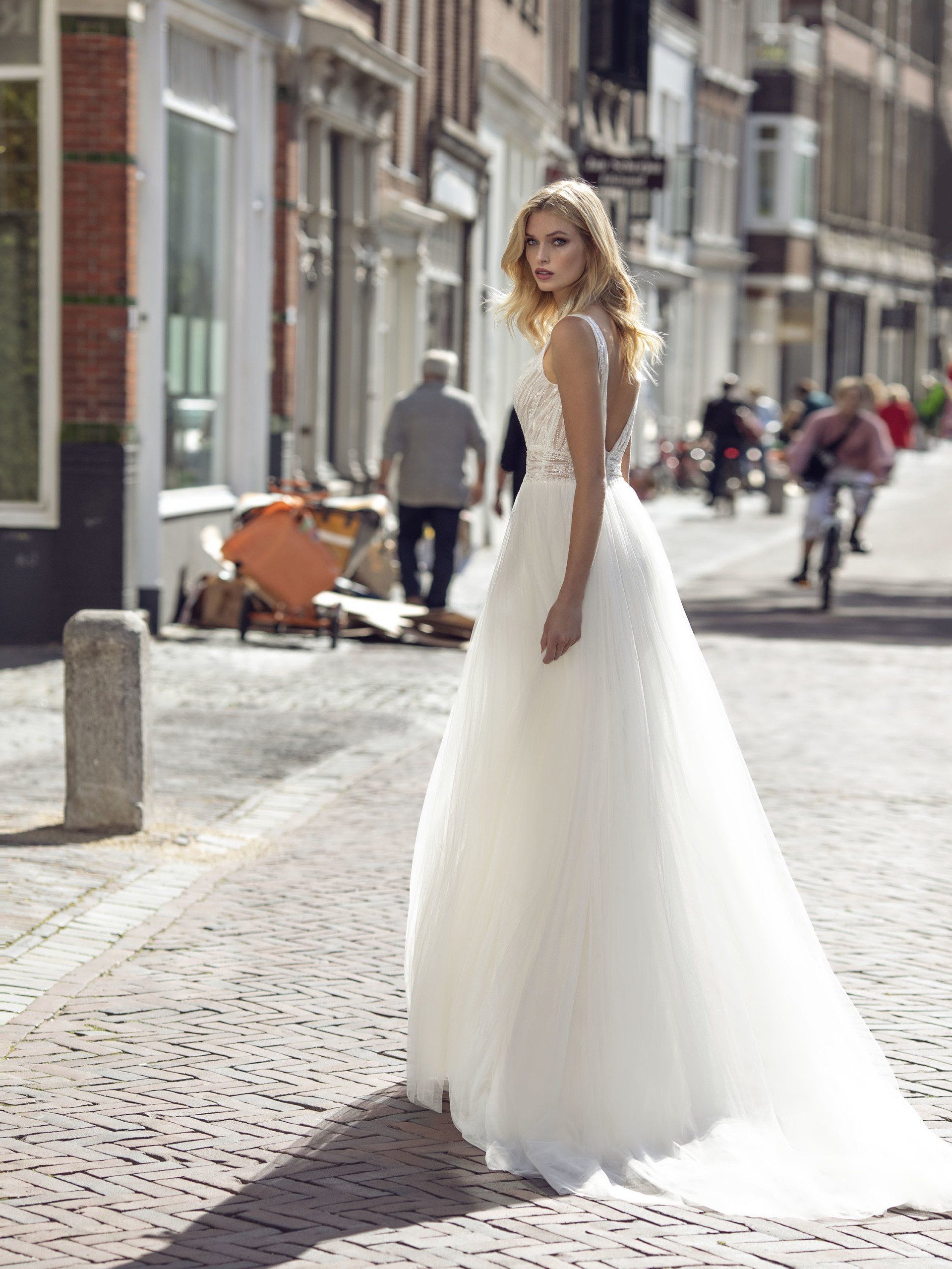 Eine Frau in einem Brautkleid steht auf einem Bürgersteig.