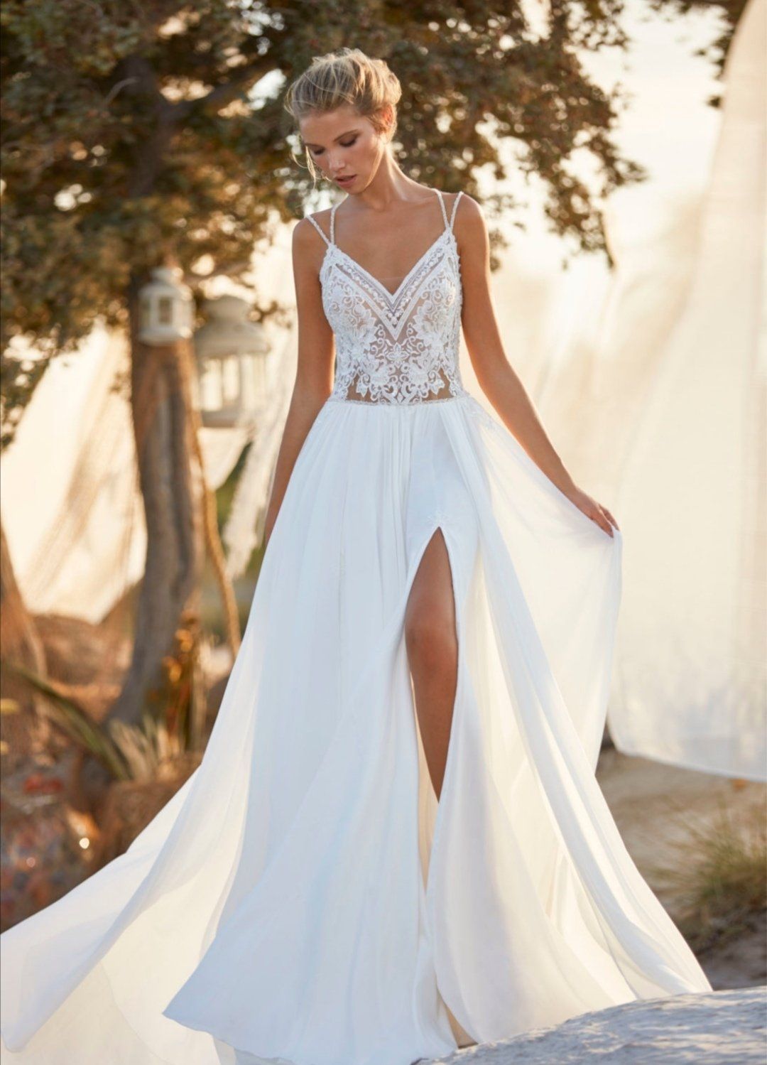 Eine Frau in einem weißen Kleid mit hohem Schlitz steht auf einem Felsen.