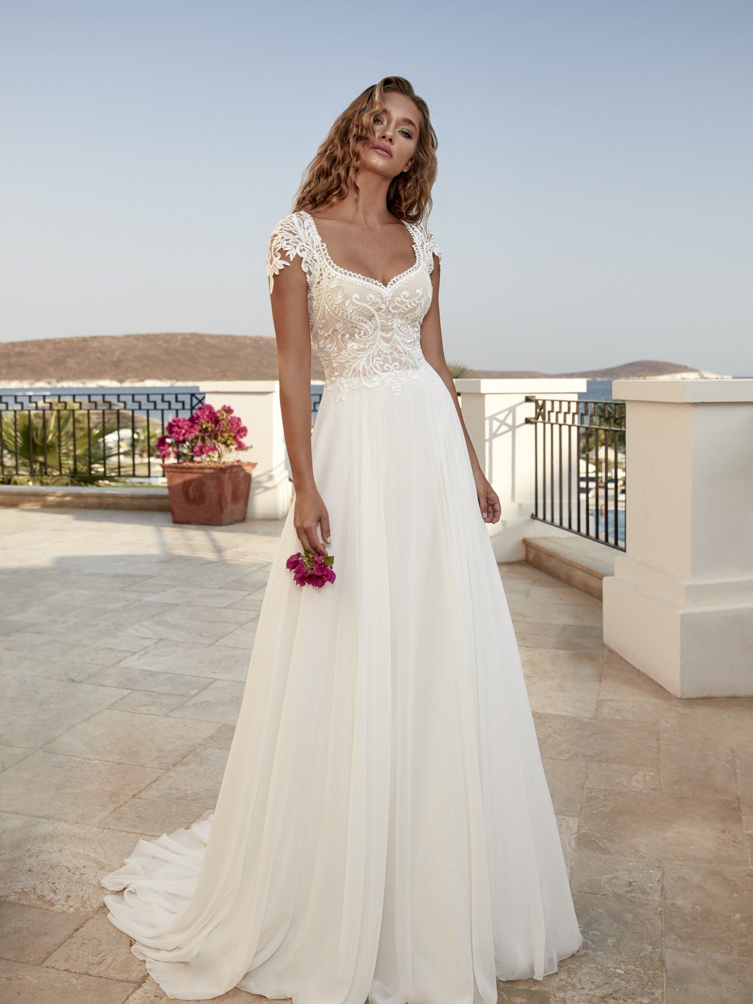 Eine Frau in einem weißen Brautkleid hält einen Blumenstrauß.