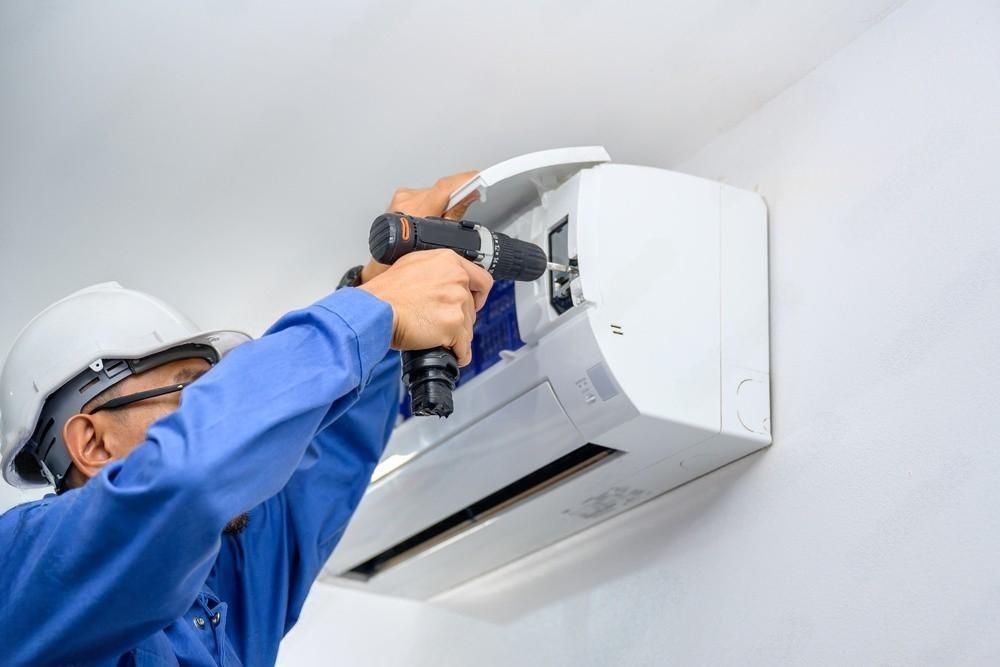 a man is installing an air conditioner on a wall .