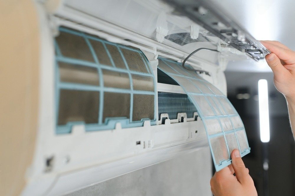 a person is cleaning the filter of an air conditioner .