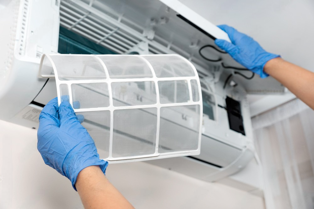 a person wearing blue gloves is cleaning an air conditioner .