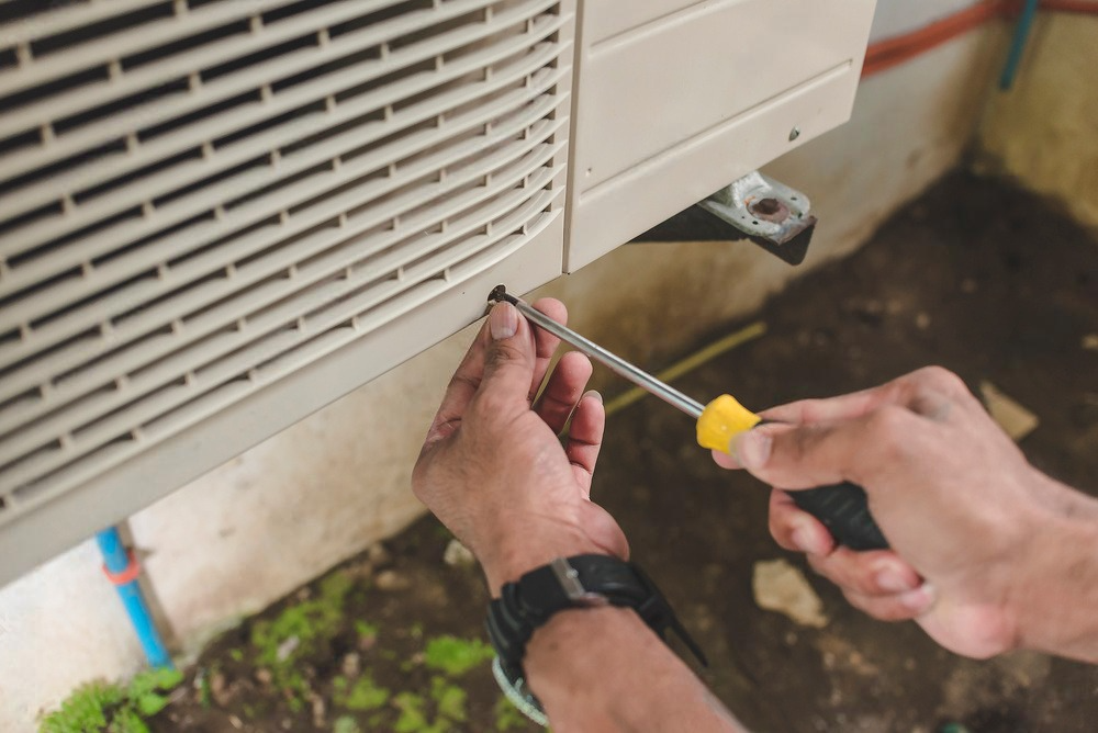 a man is fixing an air conditioner with a screwdriver .