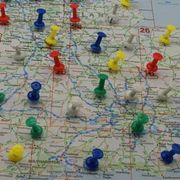 Colorful pushpins scattered across a printed map, marking locations and routes.